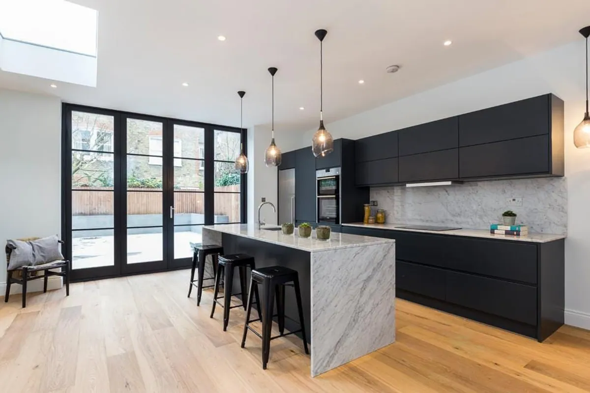 Dark kitchen with Crittall doors, marble island and dining area, London